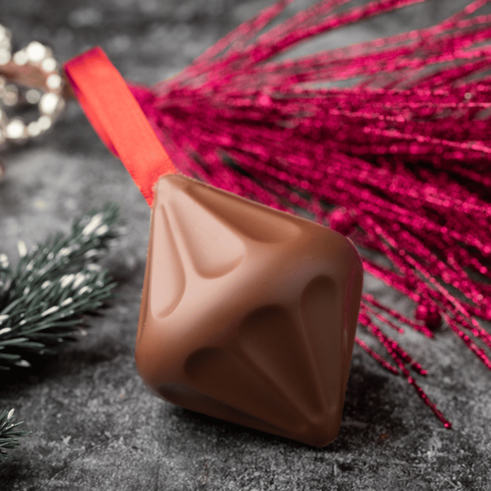 Aaraya Chocolates' Christmas Tree Ball, a luxurious chocolate masterpiece adorned with edible gold leaf for a festive and opulent holiday indulgence. Rich cocoa layers create a sensory journey, offering an exquisite treat for the season's celebrations.