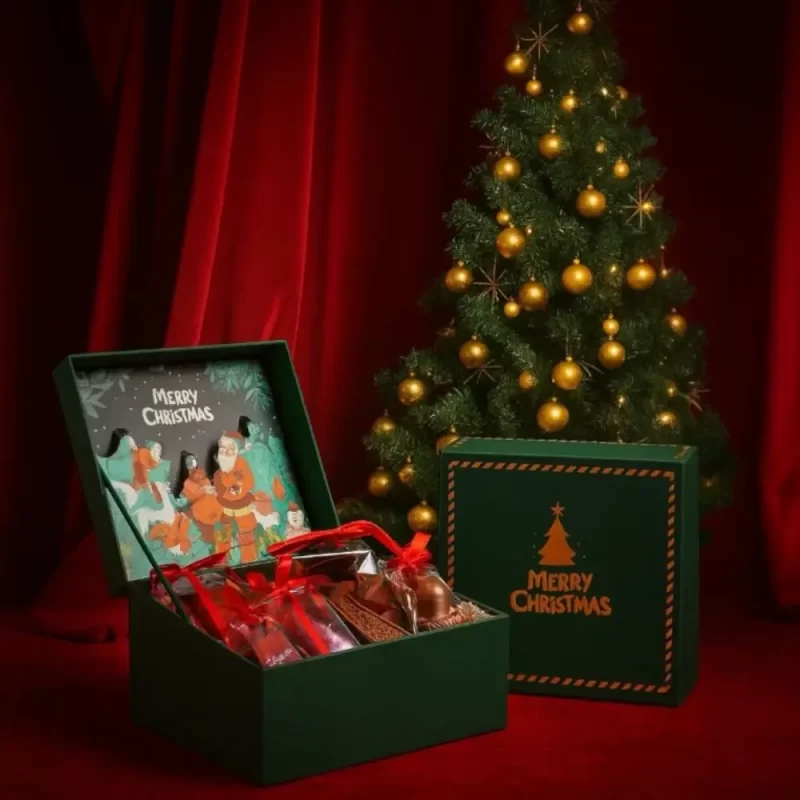 Luxury Christmas chocolate hamper by AARAYA featuring handcrafted festive chocolate figurines and gourmet chocolates presented in a premium green gift box.