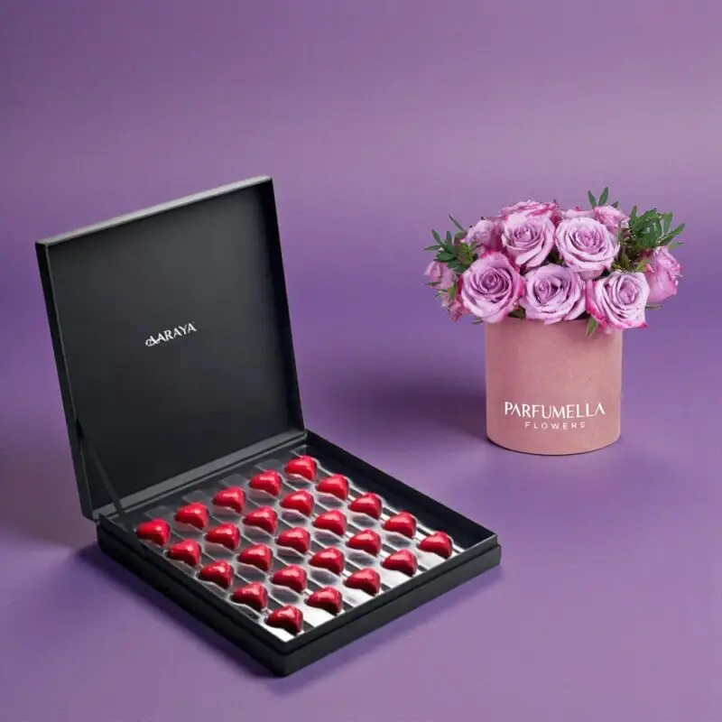 The AARAYA® Premium Valentine’s Chocolate Box with Pink Rose Hatbox is a refined expression of romance, elegance, and artisanal craftsmanship. Curated for those who appreciate understated luxury, this premium Valentine’s gift set brings together handcrafted heart chocolates and a delicate rose hatbox arrangement for a truly memorable gifting experience.